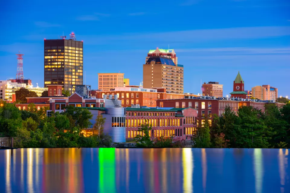 The downtown of Mancheste, New Hampshire is nestled against the Merrimack River in the final light of day.
